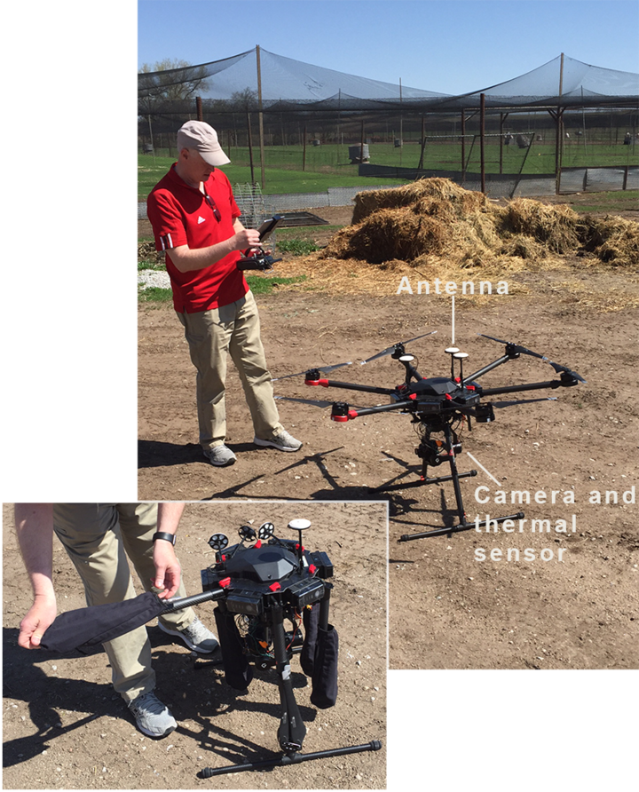 A drone pilot uses a handheld controller to ready a drone equipped with a camera and thermal sensor to fly over a farm. 