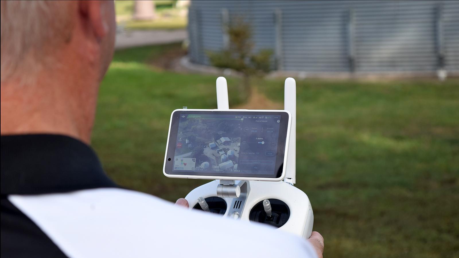 Drone operator looking at the screen of the controller while flying the drone.
